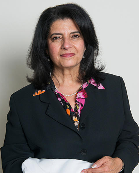 Marsha Moses is wearing a black blazer and multicolor floral blouse. She is holding her white BCH coat.