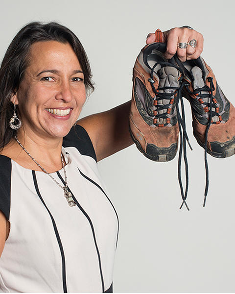 Joia Mukherjee is holding up a pair of roughed up sneakers covered in dirt.