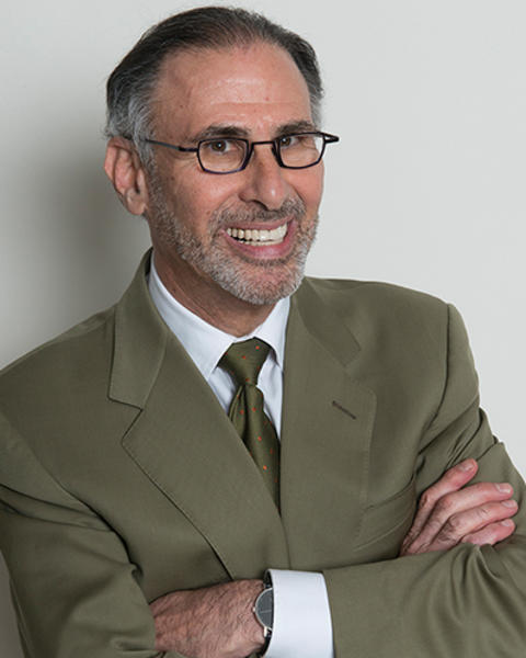 Lee Nadler is wearing a green blazer, white shirt, and green tie. He also has a matching green watch.