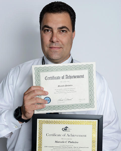 Marcelo Pinheiro is holding up two certificates of achievements from courses at The Center for Workplace Development.