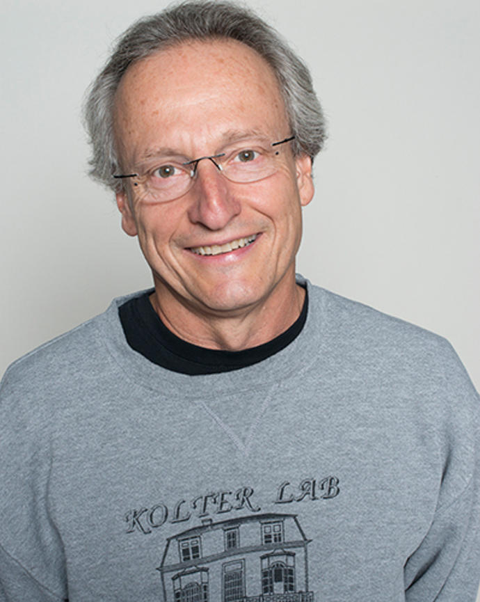 Roberto Kolter is wearing a gray sweatshirt that says, "Kolter Lab Maine Event" and has a picture of the William Dean Howells House in Kittery Point on it.