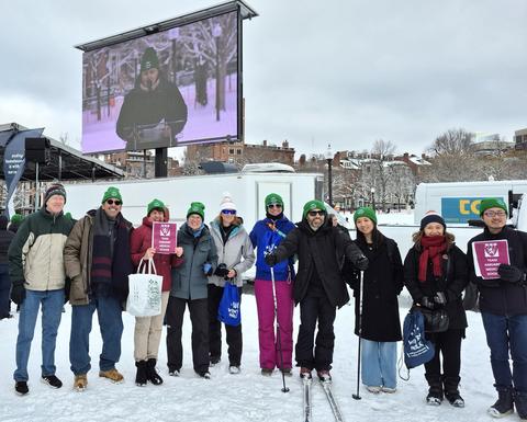 The 2025 Harvard Longwood Campus team stands bundled up in the snow on the Boston Common.
