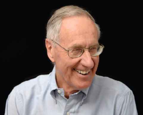 Frederick Lovejoy has short gray hair and glasses. He is wearing a light gray shirt and smiling towards the right.