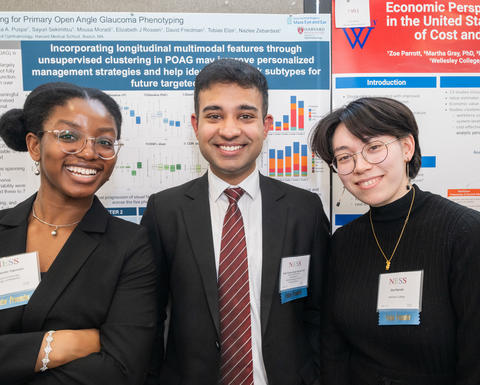 Three NESS presenters pose in front of some research posters. 