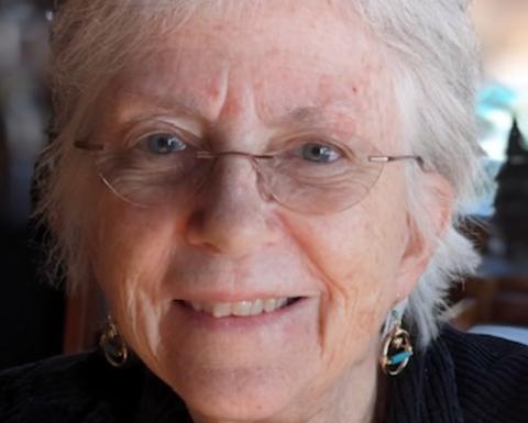 Anne Young has short white hair and is wearing frameless glasses.