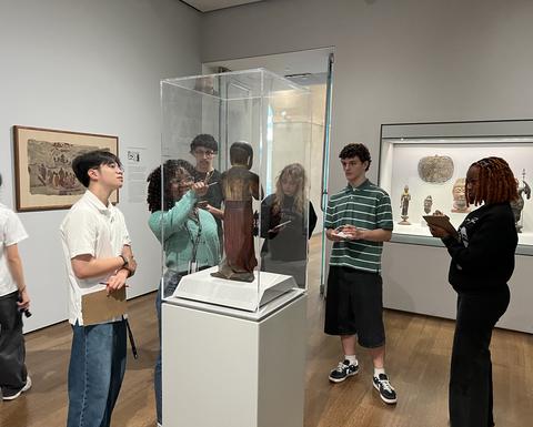 A few Project Success students observe a figurine displayed in a glass case at the Harvard Art Museum.